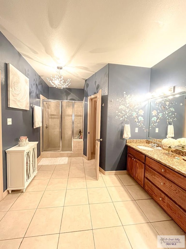 bathroom with tile patterned flooring, vanity, a shower with door, and an inviting chandelier