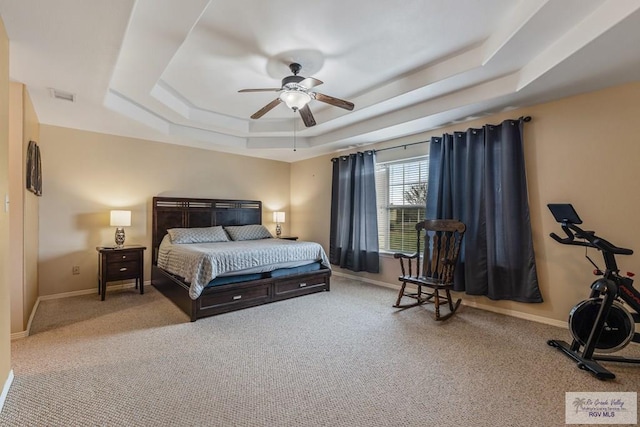 bedroom with a raised ceiling, light carpet, and ceiling fan