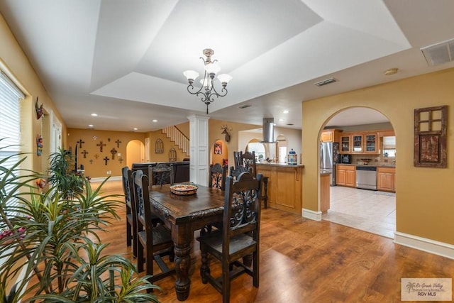 dining room featuring an inviting chandelier, a tray ceiling, and light hardwood / wood-style floors