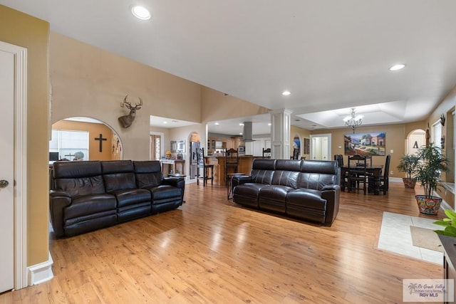 living room featuring a chandelier, light hardwood / wood-style flooring, and ornate columns