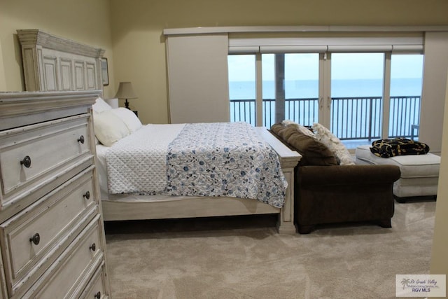 bedroom with a water view, light carpet, access to outside, and multiple windows