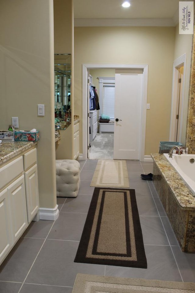 bathroom with tile patterned floors, vanity, a relaxing tiled tub, and crown molding