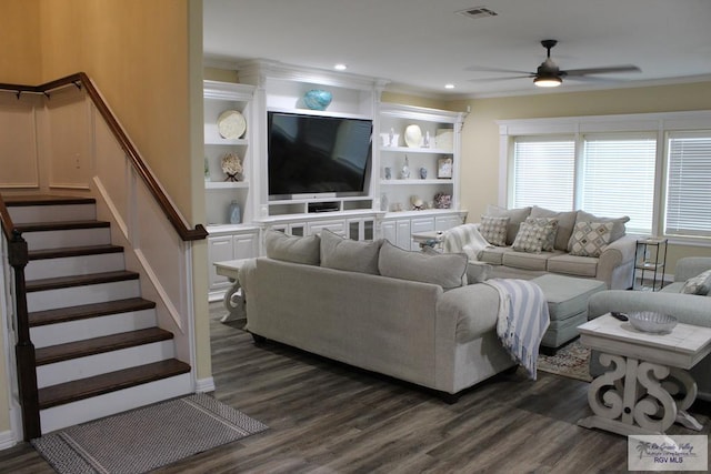 living room featuring built in features, crown molding, ceiling fan, and dark wood-type flooring