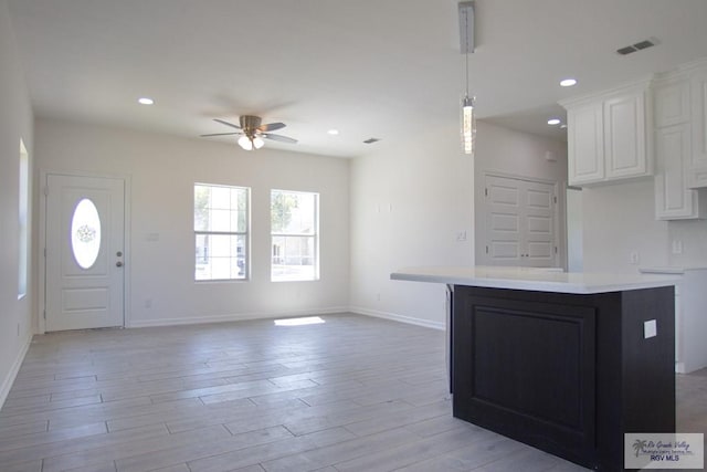 kitchen featuring ceiling fan, white cabinets, light hardwood / wood-style floors, and a kitchen island