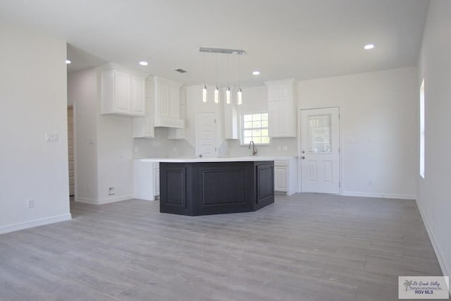 kitchen featuring a center island, white cabinets, decorative light fixtures, and light wood-type flooring