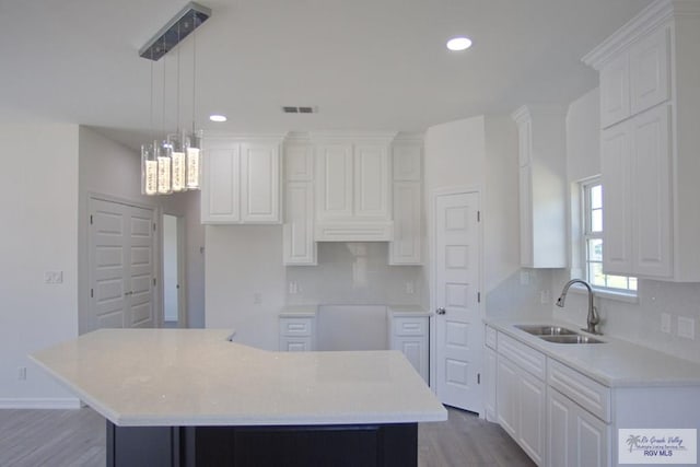 kitchen featuring sink, wood-type flooring, a center island, white cabinetry, and hanging light fixtures