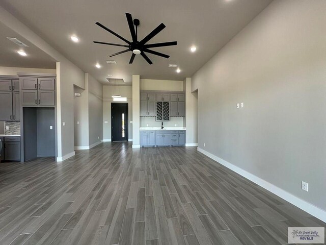 unfurnished living room with ceiling fan, sink, and dark hardwood / wood-style floors