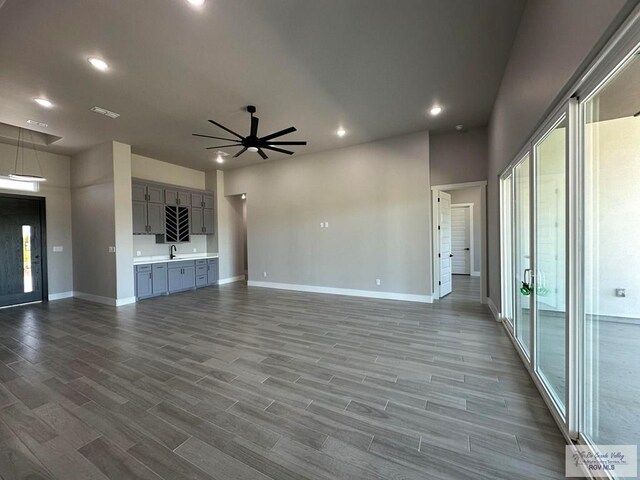 unfurnished living room featuring hardwood / wood-style flooring, ceiling fan, and sink