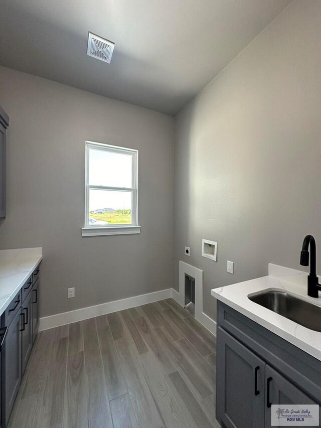 laundry area with sink, hookup for a washing machine, cabinets, light hardwood / wood-style floors, and electric dryer hookup