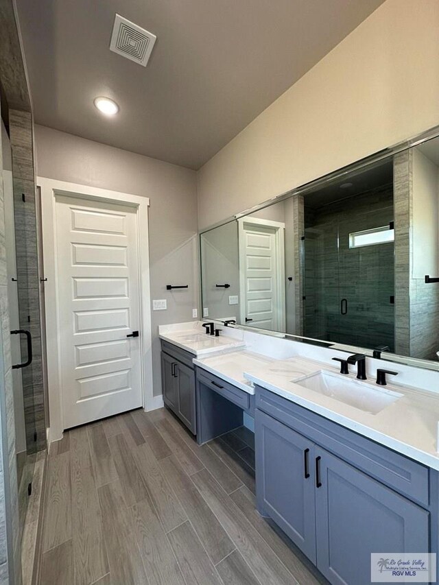 bathroom with hardwood / wood-style floors, vanity, and a shower with door