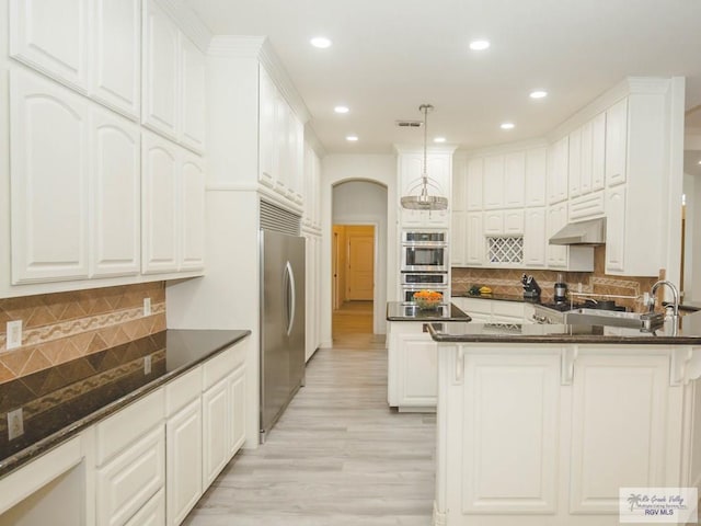 kitchen with white cabinetry, light hardwood / wood-style flooring, decorative light fixtures, decorative backsplash, and appliances with stainless steel finishes