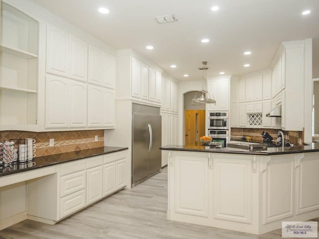 kitchen featuring white cabinets, appliances with stainless steel finishes, tasteful backsplash, and light hardwood / wood-style flooring