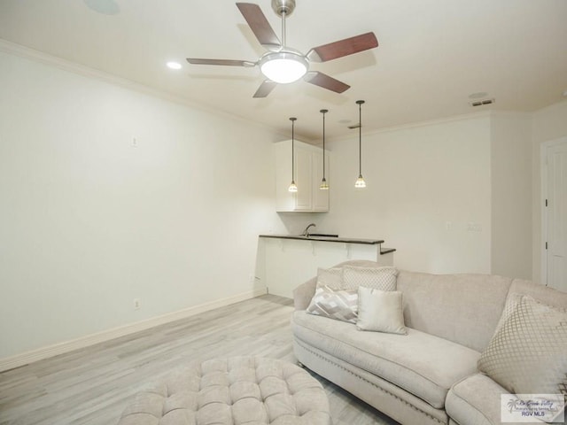 living room with light hardwood / wood-style flooring, ceiling fan, and ornamental molding