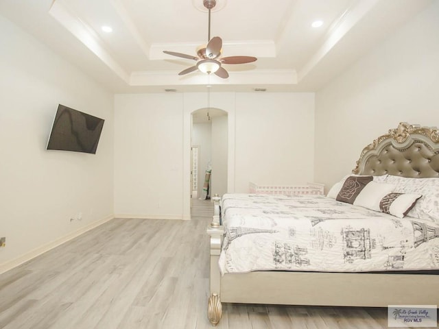 bedroom featuring ceiling fan, light hardwood / wood-style floors, and a raised ceiling