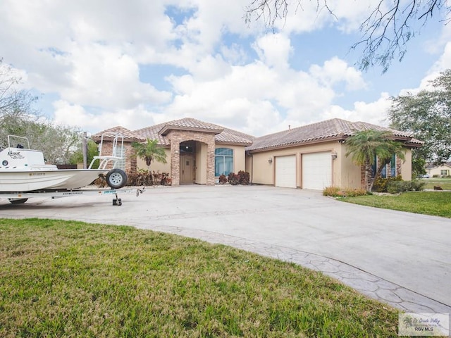 mediterranean / spanish home with a garage and a front lawn