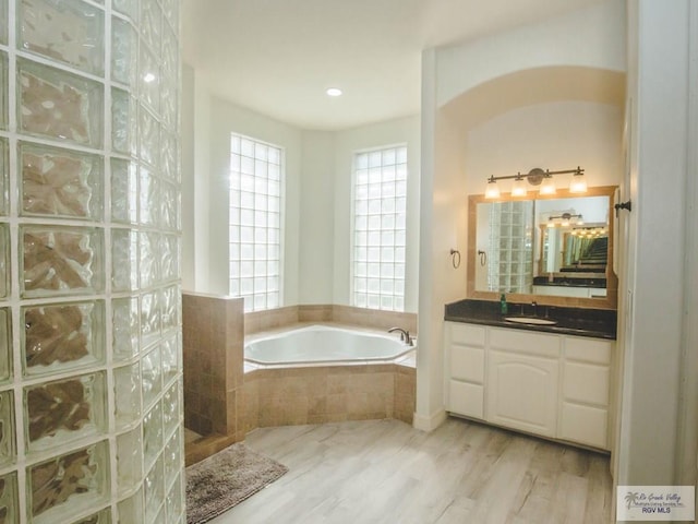 bathroom with independent shower and bath, vanity, and wood-type flooring