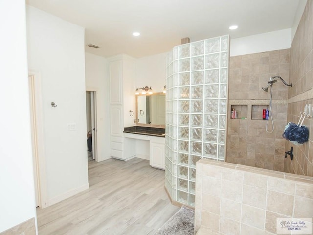 bathroom with a tile shower, hardwood / wood-style floors, and vanity