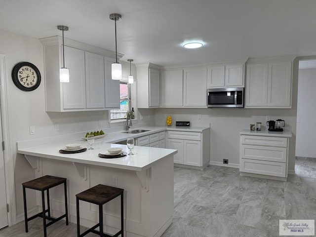 kitchen with white cabinets, a breakfast bar, kitchen peninsula, and sink