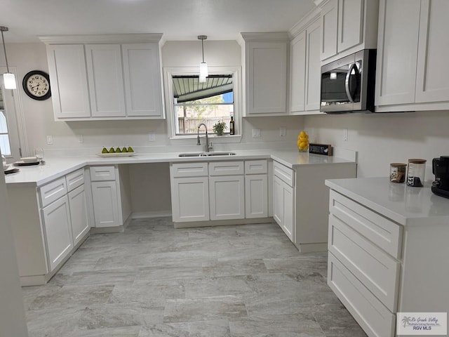 kitchen with sink, white cabinets, and hanging light fixtures