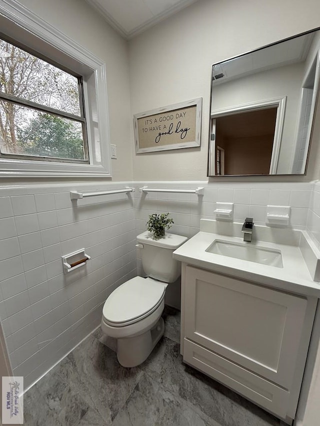 bathroom with vanity, tile walls, and toilet