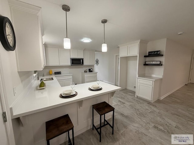 kitchen with a breakfast bar, kitchen peninsula, and white cabinets