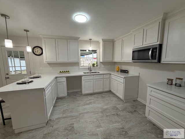 kitchen with white cabinets, decorative light fixtures, kitchen peninsula, and sink