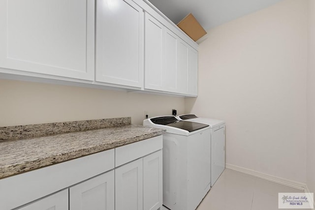 laundry area with washing machine and dryer, light tile patterned floors, and cabinets