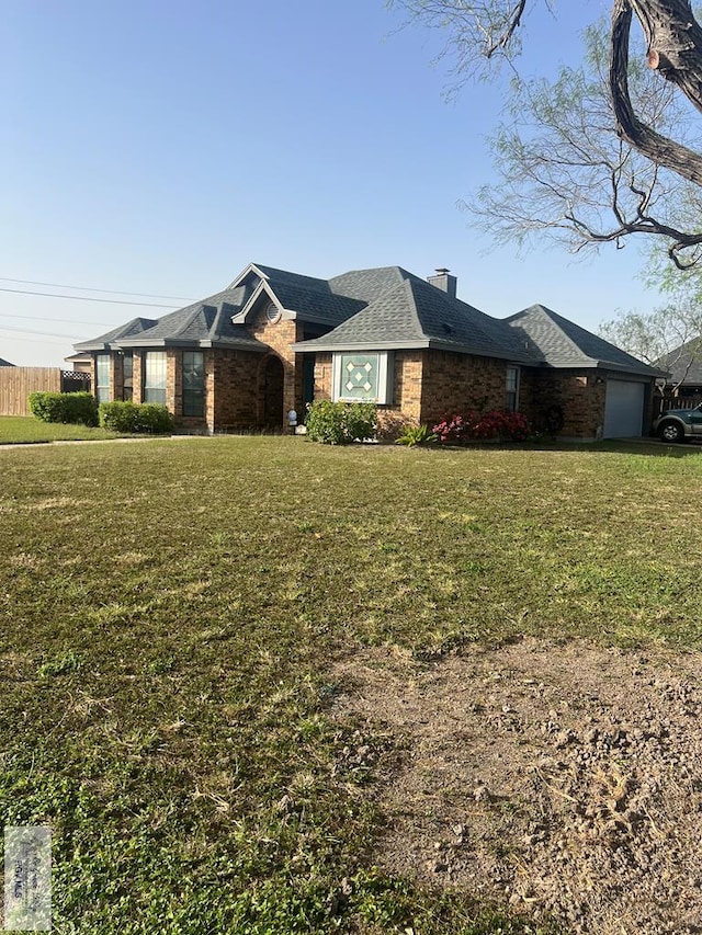 view of front of property featuring a chimney, a front lawn, a garage, and brick siding