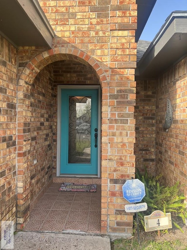 view of exterior entry featuring brick siding