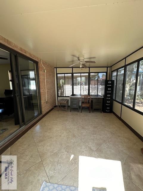 unfurnished sunroom featuring ceiling fan