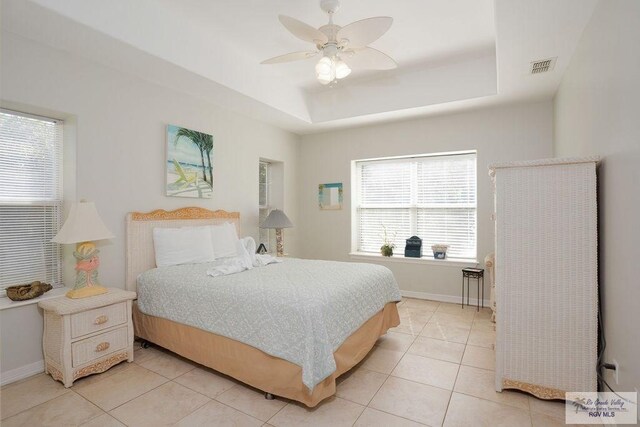 6401 Fountain Way S, Padre Island, TX 78597 - bedroom with a tray ceiling, light tile patterned floors, and a ceiling fan