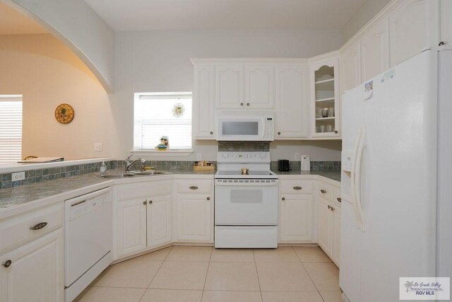 6401 Fountain Way S, Padre Island, TX 78597 - kitchen with white appliances, white cabinets, arched walkways, light tile patterned flooring, and glass insert cabinets