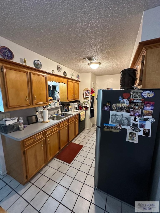 kitchen with dishwasher, a textured ceiling, stainless steel fridge, light tile patterned floors, and sink