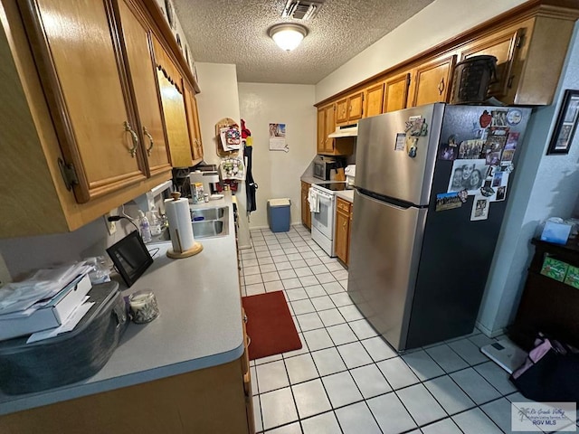 kitchen with sink, light tile patterned flooring, stainless steel appliances, and a textured ceiling