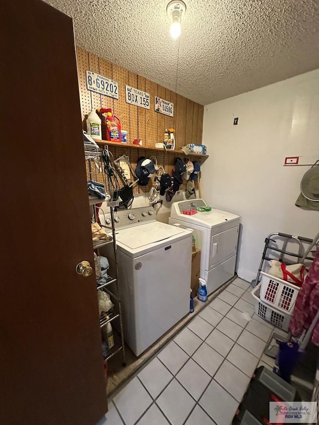 laundry room featuring washing machine and dryer, light tile patterned floors, and a textured ceiling