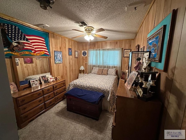 bedroom featuring carpet floors, a textured ceiling, wood walls, and ceiling fan