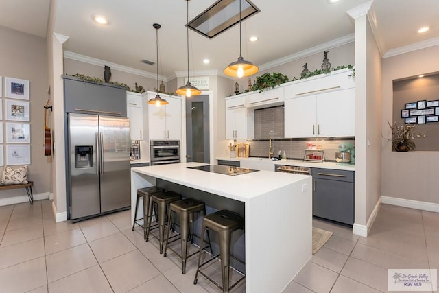 kitchen with pendant lighting, a breakfast bar, backsplash, light countertops, and appliances with stainless steel finishes