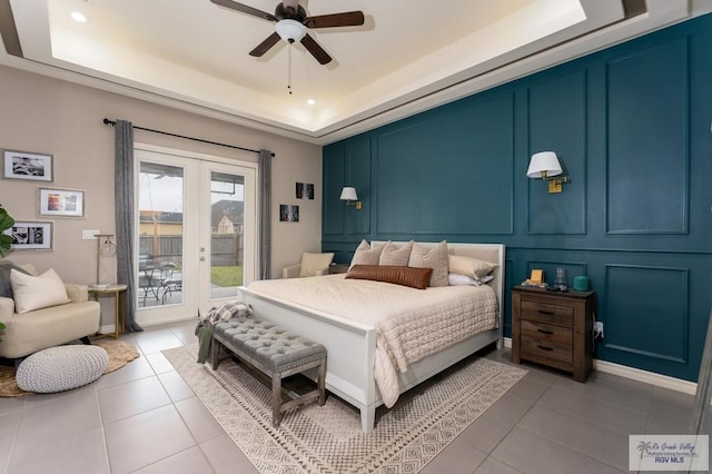 bedroom featuring french doors, light tile patterned flooring, access to outside, a decorative wall, and a raised ceiling