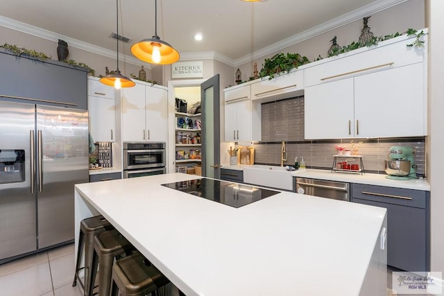 kitchen featuring a sink, stainless steel appliances, tasteful backsplash, crown molding, and light countertops