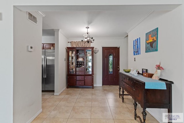 tiled foyer with crown molding and a notable chandelier