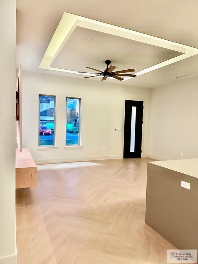 spare room featuring light parquet floors, a raised ceiling, and ceiling fan