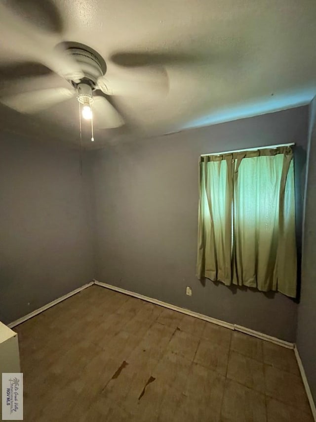 spare room with a ceiling fan and baseboards