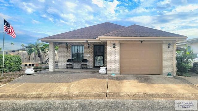 180 Chippewa Cir, Harlingen, TX 78555 - ranch-style home with brick siding, a garage, driveway, covered porch, and a shingled roof