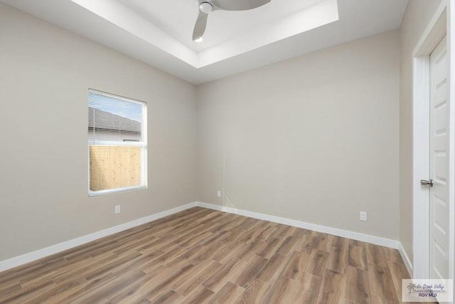 spare room with hardwood / wood-style flooring, ceiling fan, and a tray ceiling