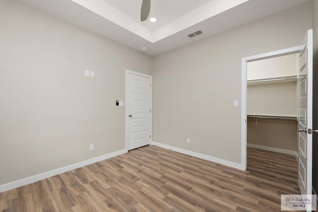 unfurnished bedroom featuring hardwood / wood-style floors, a spacious closet, and a closet