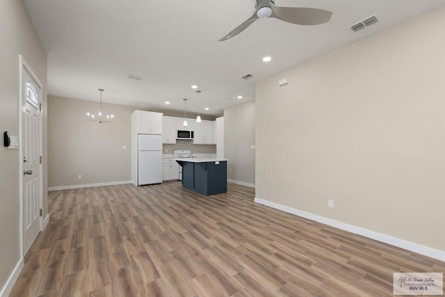 unfurnished living room with sink, ceiling fan with notable chandelier, and light wood-type flooring