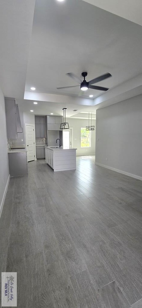 unfurnished living room featuring dark wood-style floors, baseboards, and a sink