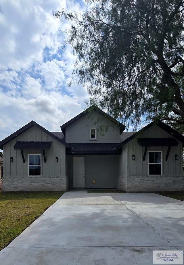 view of front of house with a garage, brick siding, board and batten siding, and concrete driveway