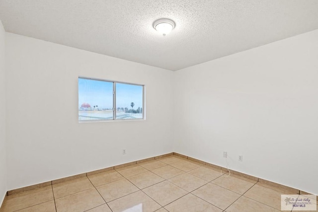 spare room with light tile patterned flooring and a textured ceiling