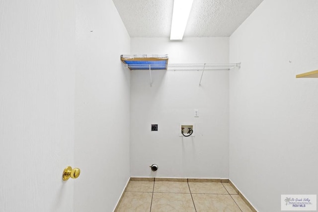 clothes washing area featuring washer hookup, hookup for an electric dryer, a textured ceiling, and light tile patterned floors